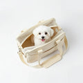 Petit chien dans un sac de transport beige avec ouvertures en maille